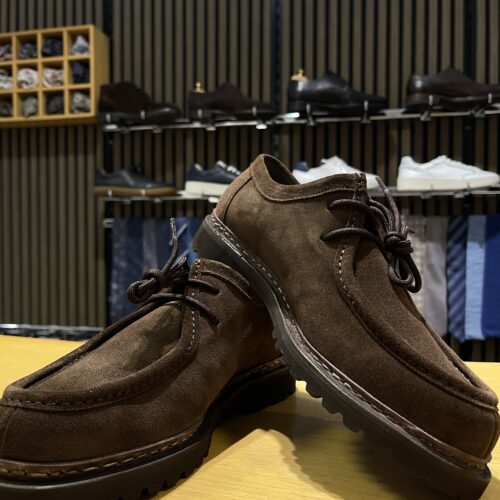 Ein Paar braune Lederschuhe vor einem Regal in einem Schuhgeschäft.