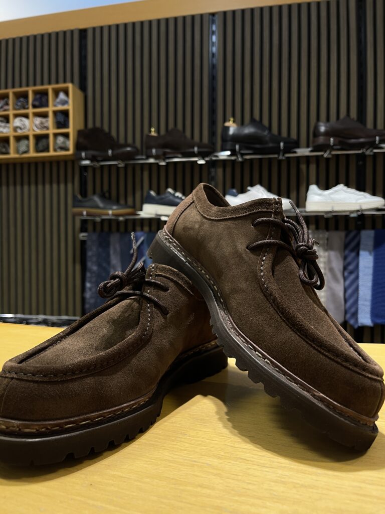 Ein Paar braune Lederschuhe vor einem Regal in einem Schuhgeschäft.
