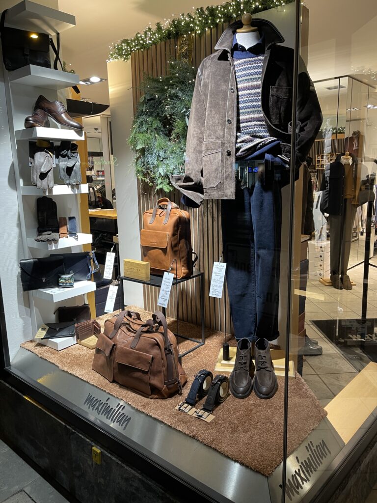 Eine männliche Schaufensterpuppe trägt braune Jacke, Strickpullover und Jeans in elegantem Look