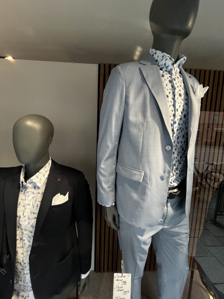 Zwei Schaufensterpuppen tragen helle Anzüge mit gemusterten Hemden und Einstecktüchern